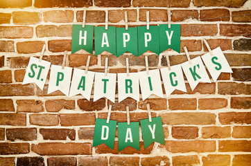 Happy St. Patrick's Day banner lettering on red, old orange brick wall background. Irish national colors greeting postcard template.