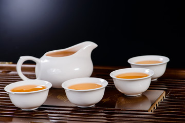 Obraz na płótnie Canvas Chinese tea service cup of hot green tea, close-up, on black bac