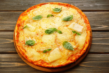 Tasty pizza decorated with basil  on wooden background, close up