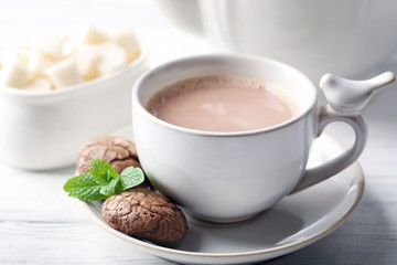 Cup of cocoa with chocolate chip cookies and mint on light background