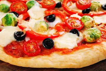 Delicious pizza with cheese and vegetables on wooden cutting board closeup