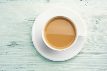 Porcelain cup of tea with milk on white wooden background
