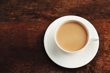 Porcelain cup of tea with milk on wooden background