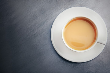 Porcelain cup of tea with milk on gray background