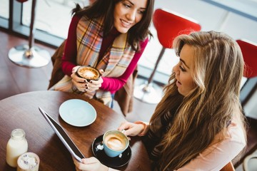 Friends using tablet together in cafe