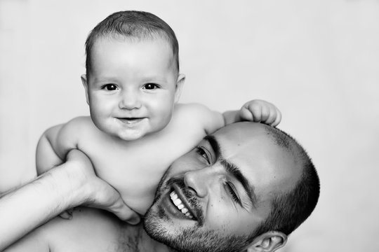 smiling baby boy sitting on father's shoulder over white background