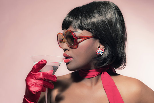 Retro 60s fashion african woman with sunglasses holding cocktail