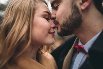 Stylish Loving wedding couple kissing and hugging in a pine forest near retro car