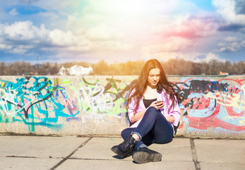 Young pretty teenage woman use her phone in city park near river 