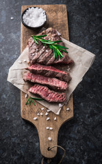 Grilled beef steak with rosemary and salt on cutting board