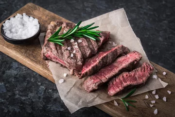 Foto auf Acrylglas Steakhouse Gegrilltes Rindersteak mit Rosmarin und Salz auf Schneidebrett
