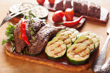 Delicious beef steak with vegetable over wooden table close-up