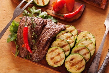 Delicious beef steak with vegetable over wooden table close-up
