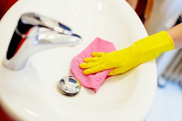 Female hands with yellow rubber protective gloves cleaning sink