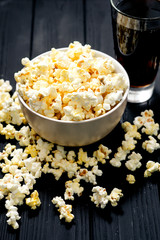 cheese popcorn in the bowl with a glass of cola or beer and potato chips on the wooden background