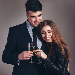 Portrait young couple with glass of champagne, wear evening dress and suit, glamour vogue style, sensual looking at camera, sitting indoors