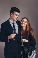 Portrait young couple with glass of champagne, wear evening dress and suit, glamour vogue style, sensual looking at camera, sitting indoors