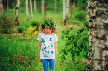 child girl in summer forest. Idea for nature crafts with kids - leaf print shirt and natural wreath. Teaching kids to love nature.