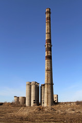 The ruins of the destroyed factory with a tall chimney fixed in