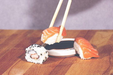 An image of eating sushi with chopsticks. Image has a vintage effect applied.
