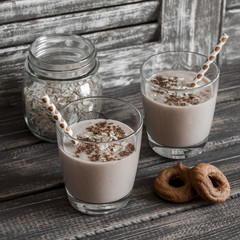 Healthy drink - banana and oatmeal smoothie in a glass on dark wooden background, rustic style