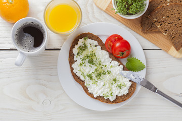 healthy spring summer low fat breakfast with orange juice,coffee,bread,cottage cheese, cress and tomatos at white wooden table
