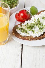 healthy spring summer low fat breakfast with orange juice,coffee,bread,cottage cheese, cress and tomatos at white wooden table