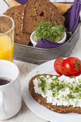Fototapeta na wymiar healthy spring summer low fat breakfast with orange juice,coffee,bread,cottage cheese, cress and tomatos at white wooden table