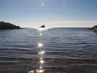 Brillo de reflejos con forma de estrella y destellos en el mar azul con islotes en el horizonte,...