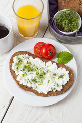 healthy spring summer low fat breakfast with orange juice,coffee,bread,cottage cheese, cress and tomatos at white wooden table