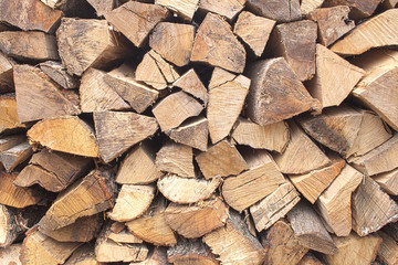Background of chopped firewood stacked up on top of each other in a pile