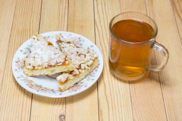 Mug of tea with a plate of cake on a wooden board, breakfast