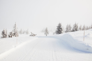 Snow covered norwegian road and landscape disappears in the mist