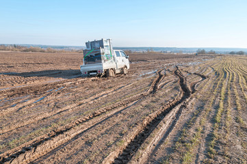 Off-road truck with furniture settles down in mud on dirty road in fallow field
