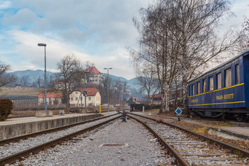 Fototapeta premium Kamnik, Slovenia - January 25, 2016. Small town railway station with restaurant wagon on track and Castle Zaprice on the background.