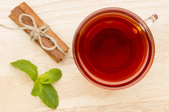 Glass cup of tea with mint and cinnamon stick on the wooden table