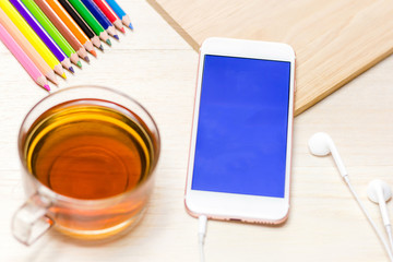 Office workspace with keyboard notepad coffee of cup and smartphone on wood table.