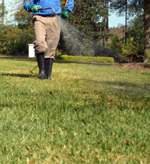 Vertical photo of a lawn care professional spraying a yard in the springtime