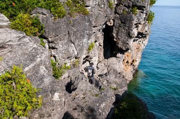 teenage boy climbing down rocks into the grotto at Bruce Peninsula National Park