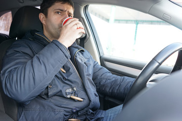 Man drinking coffee in the car