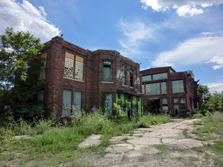 Abandoned old brick buildings with overgrown weeds and broken windows - landscape color photo