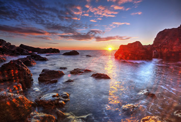 Beautiful sunrise on rocky shore and dramatic sky clouds © phadventure