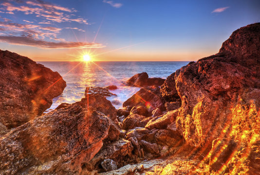 Beautiful sunrise on rocky shore and dramatic sky clouds