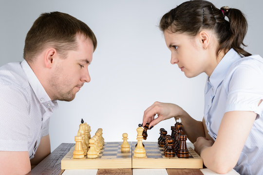 Woman playing the black pieces in chess against men