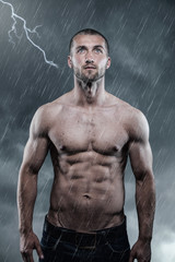 Mann mit Sixpack genießt Regen und Blitz  