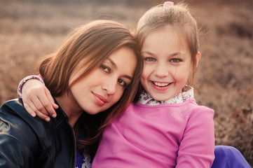 lifestyle capture of happy mother and preteen daughter having fun outdoor. Loving family spending time together on the walk. Cozy weekend.