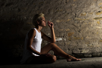 Lonely young woman sitting on the street, looking severely depressed.
