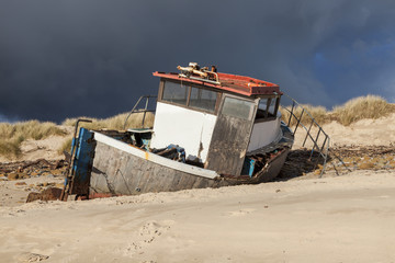 Abandoned and wrecked old fishing boat at the mouth of River Wansbeck, on the coast of Northumberland, England, UK.