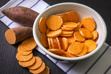 Raw sweet potato with at the wooden table