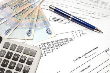 Calculator, pen, money and primary documents for payroll